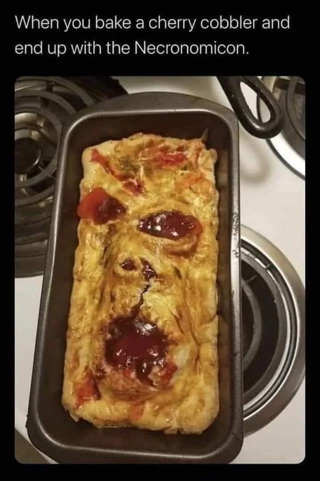 A loaf pan contains a baked dessert that has been shaped and topped with cherry filling to resemble a grotesque, demonic…