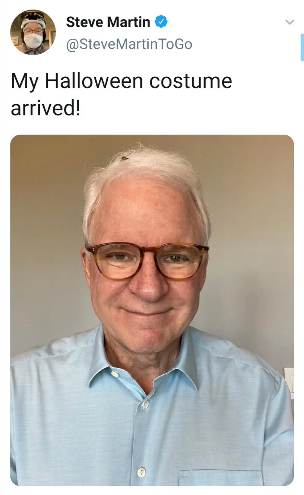 A screenshot of a tweet by Steve Martin showing him smiling while wearing a light blue button-down shirt and glasses. A…
