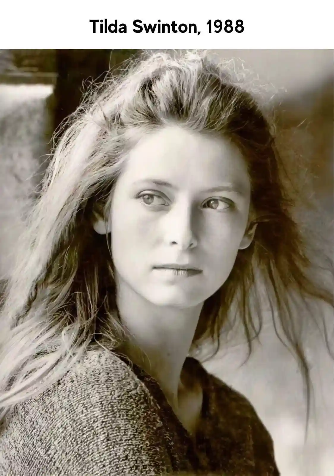 A sepia-toned, vintage-style portrait of a young woman with long, tousled hair and a neutral expression, wearing a textured…