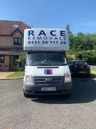A white Ford Transit van with 'RACE REMOVALS' and phone number '0131 24 111 24' on its roof sign is parked on a residential…