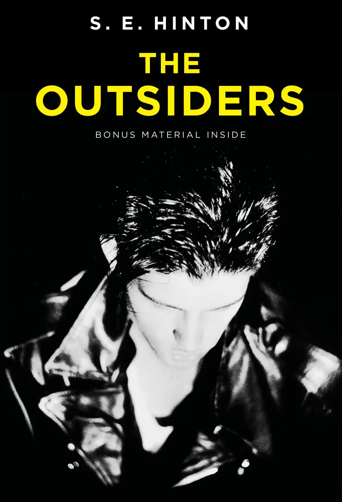 The image is a black and white book cover for 'The Outsiders' by S.E. Hinton, featuring a young man in a leather jacket…