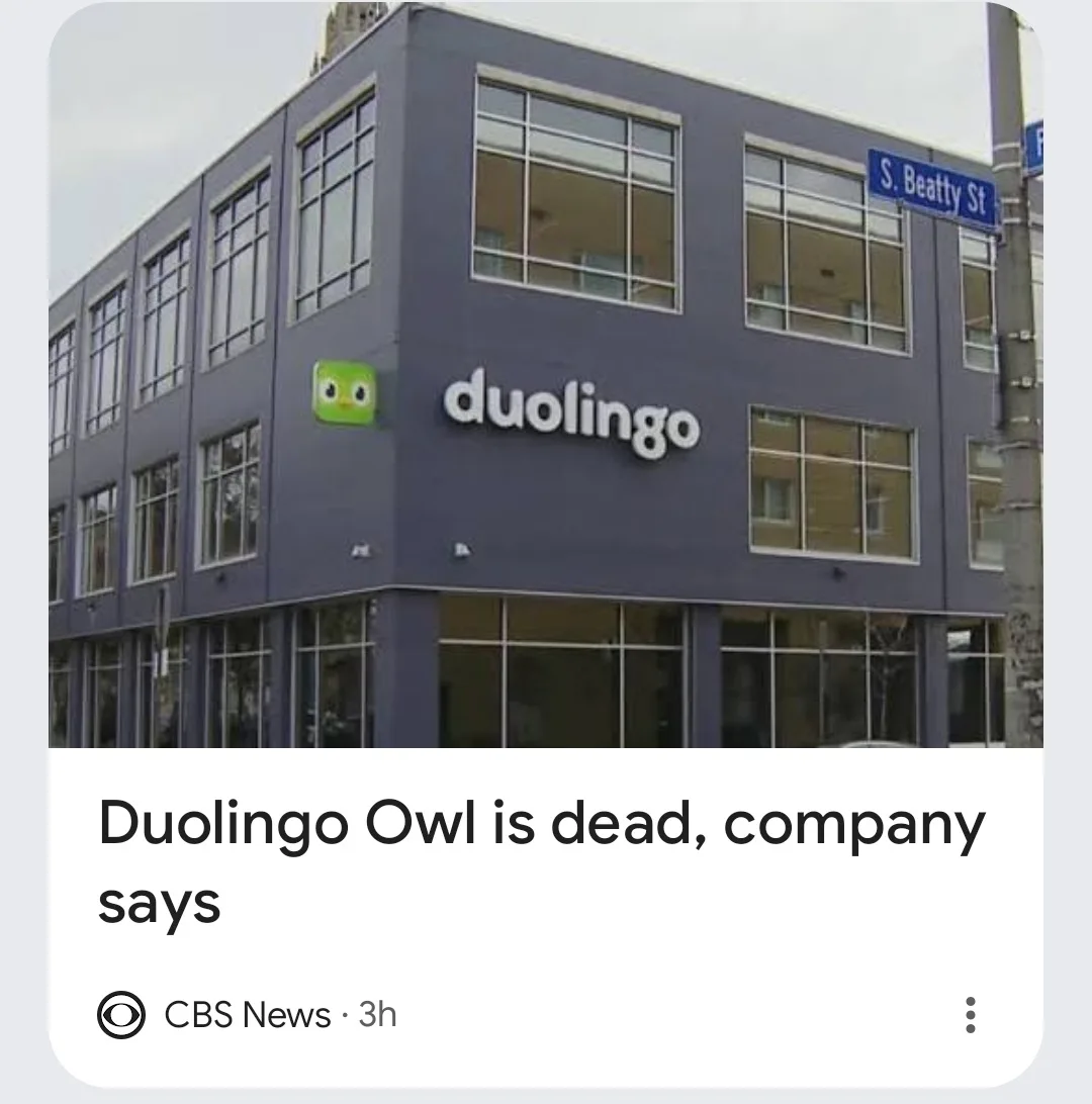 An exterior photo of a modern, dark blue Duolingo office building with the company logo and green owl mascot visible. The…