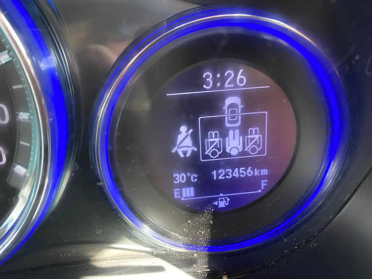 A close-up of a car's digital dashboard display with a blue illuminated bezel, showing the time as 3:26, temperature at…