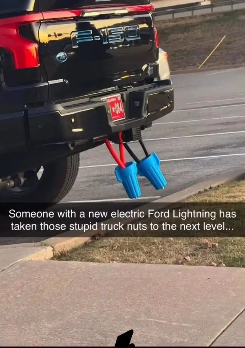 The rear of a black Ford F-150 truck is shown with its hitch extended, but instead of a trailer, it has two large blue…