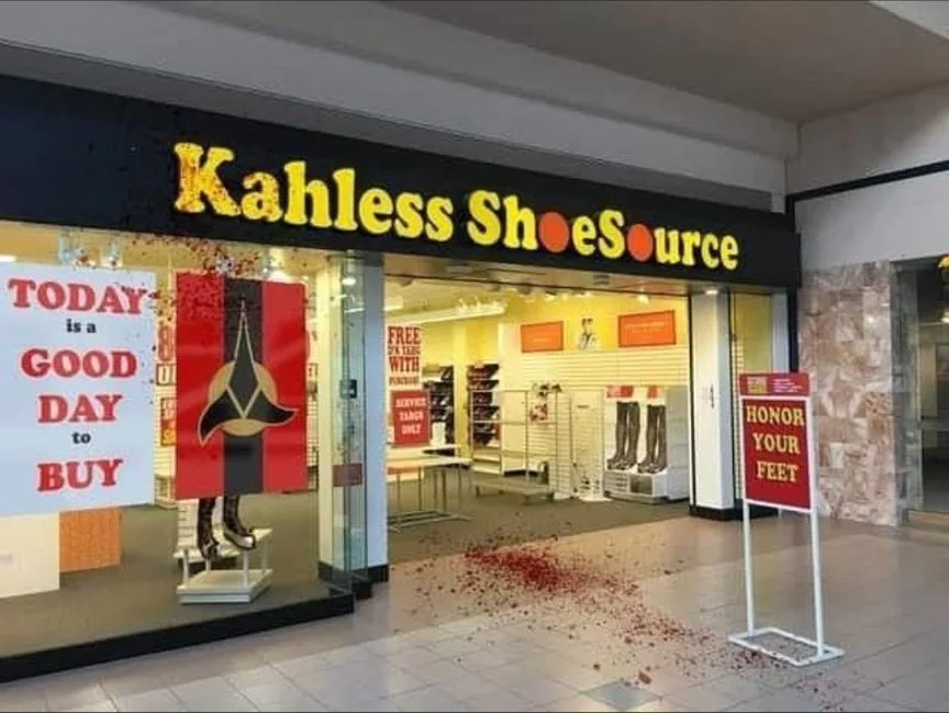 A storefront for 'Kahless ShoeSource' has red confetti scattered across the floor outside, suggesting a celebration or sale…