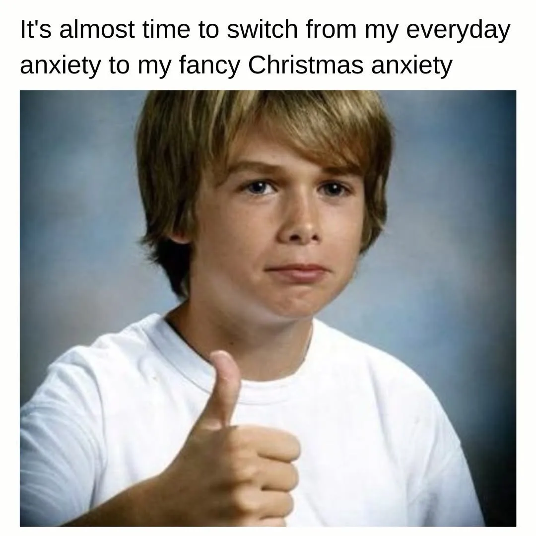 A young boy with blond hair and a white t-shirt gives a thumbs-up while looking directly at the camera with a slightly…
