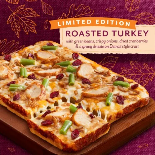 An advertisement image for a pizza featuring roasted turkey, green beans, crispy onions, dried cranberries, and gravy on a…