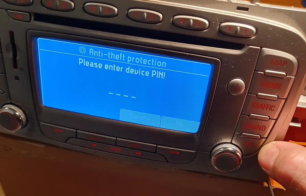 A close-up photo of a car's infotainment system screen displaying a blue message asking for a device PIN to bypass…