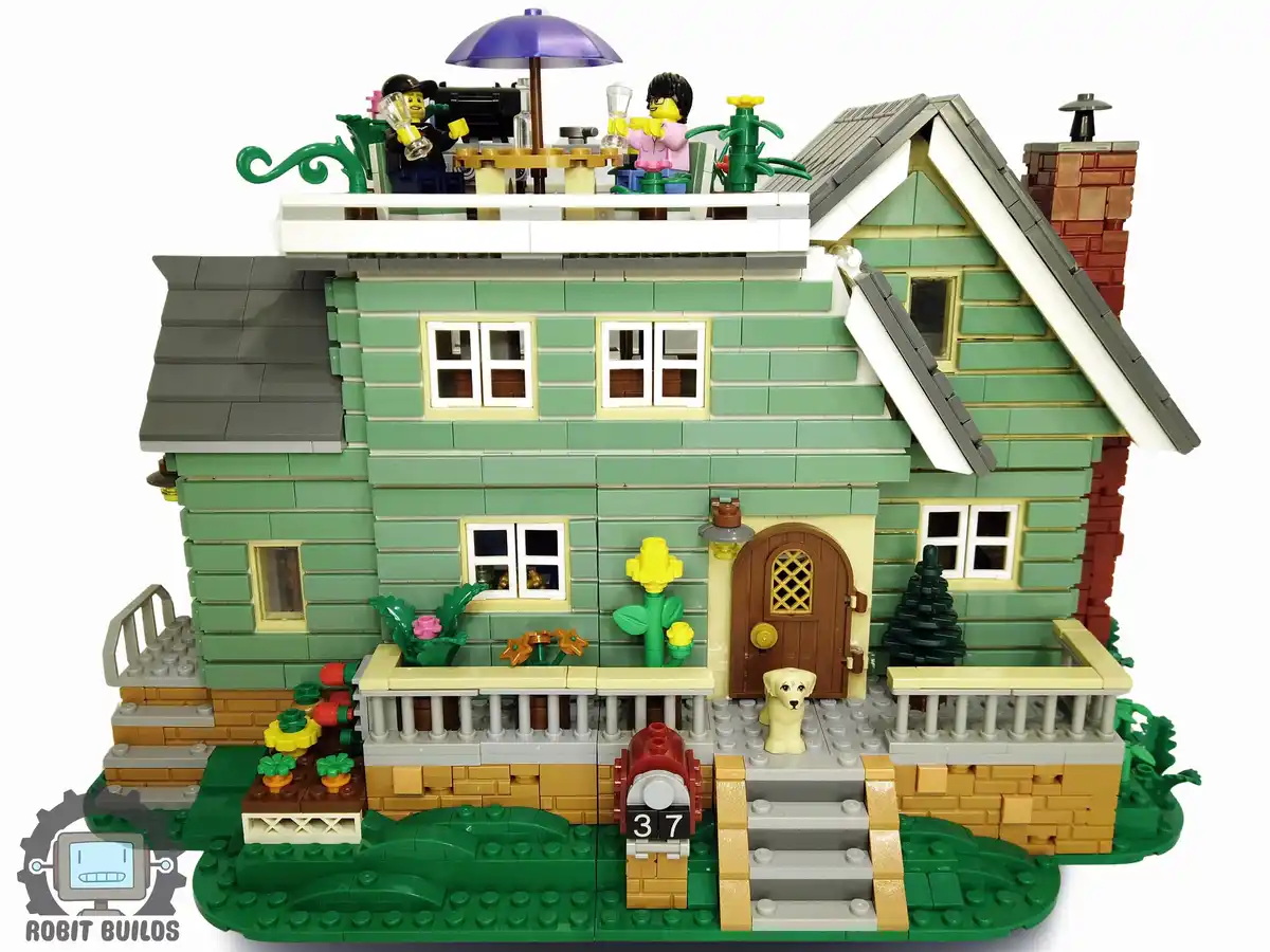 A detailed LEGO model of a green two-story house with a brown door, windows, and a chimney, featuring a small dog figurine…