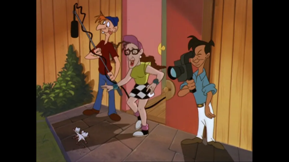 In a cartoon scene, three characters are filming a small white mouse on a tiled porch. One holds a boom mic, another a…