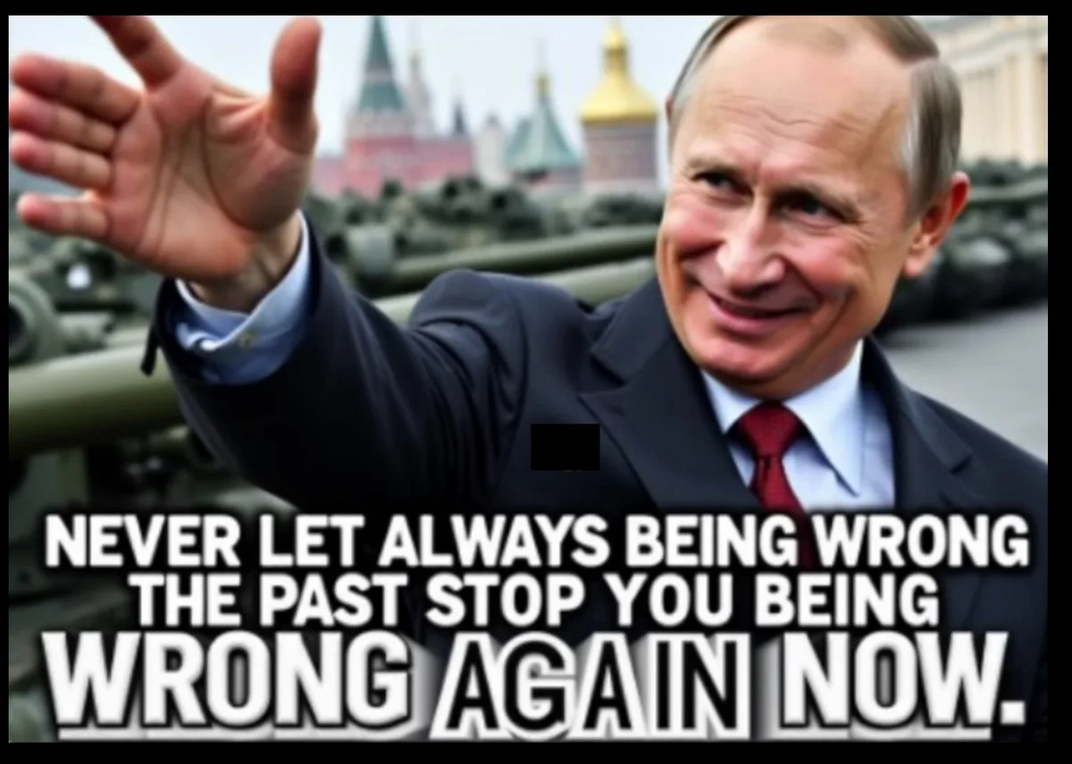 A man in a suit and red tie smiles and waves while standing in front of a line of military tanks with Kremlin spires in the…