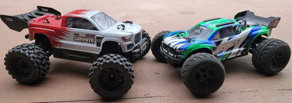 Two remote-controlled monster trucks, one red and white with 'GRANITE' branding and the other green and blue with 'VORIEKS'…
