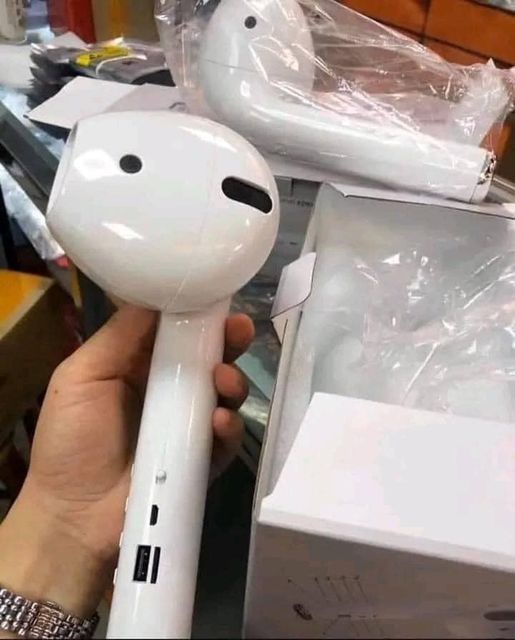 A hand holds a white hair dryer that has been modified to resemble Apple AirPods, with two circular cutouts mimicking…