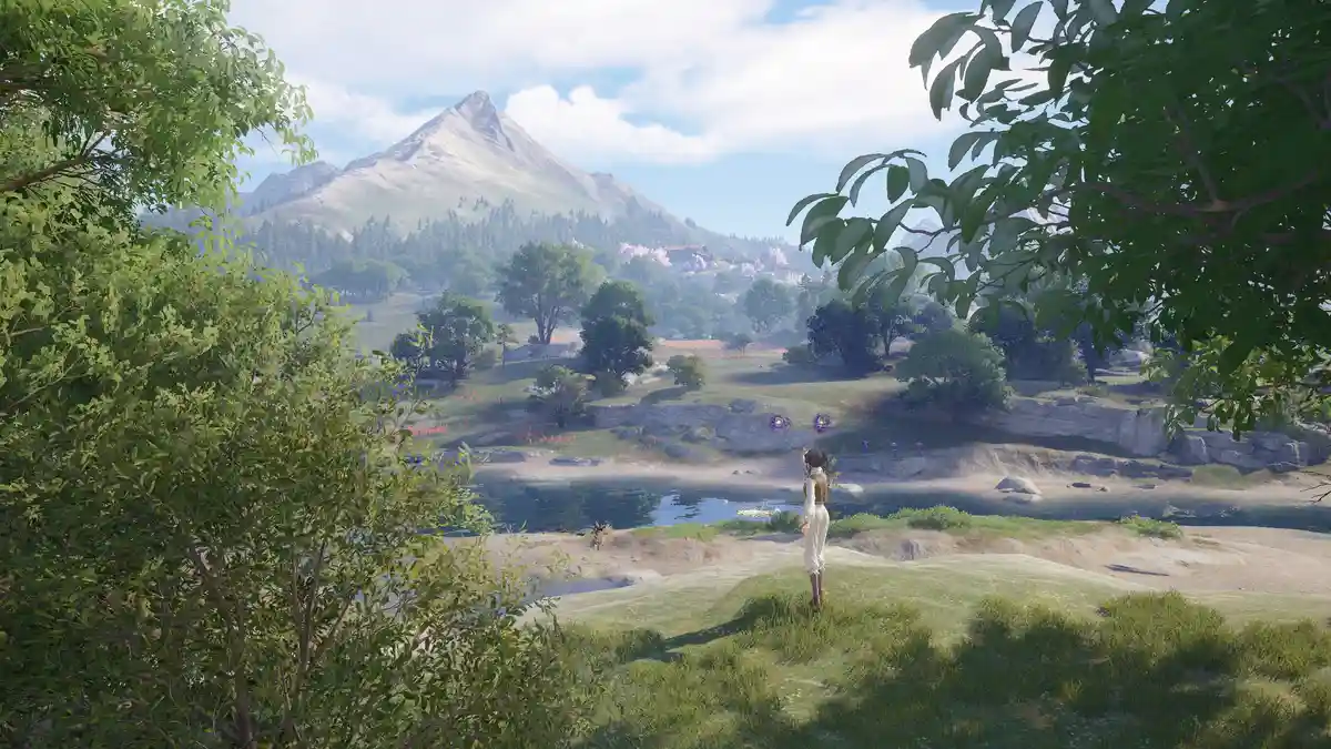 A character in a video game stands on a grassy hill overlooking a serene valley with a lake, trees, and distant mountains…