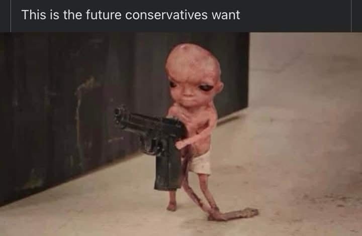 A small, emaciated, bald, pale-skinned doll-like figure with large dark eyes and a long tail stands on a concrete floor…