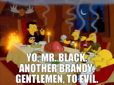 A still image from The Simpsons shows a group of characters seated around a dining table in a dimly lit room with a…