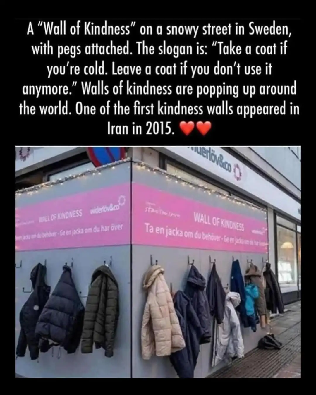 An outdoor wall in Sweden covered in hooks with various winter coats hanging on them, under a pink banner that reads 'WALL…