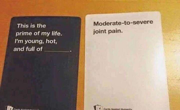 Two Cards Against Humanity cards are placed side-by-side on a wooden surface. The left card is dark blue with white text…