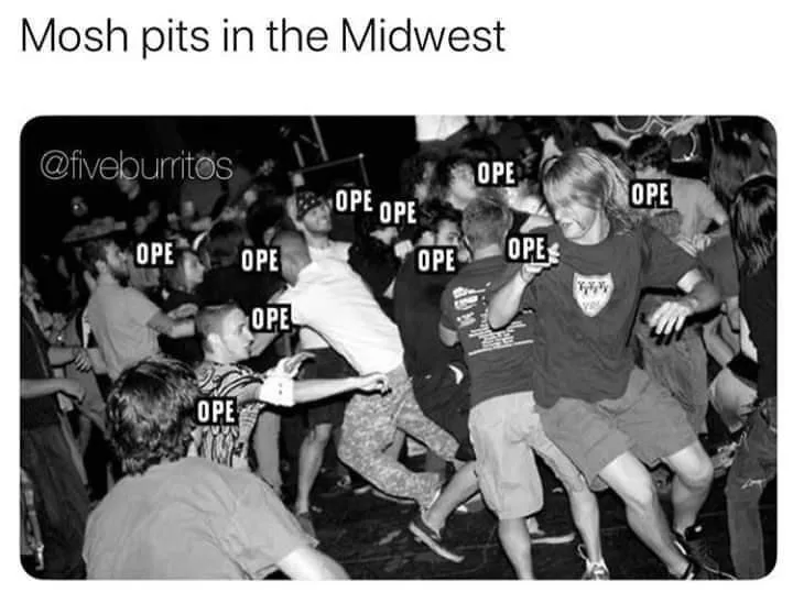 A black and white photo of a crowded, energetic mosh pit at a concert, with multiple people jumping and moving aggressively…