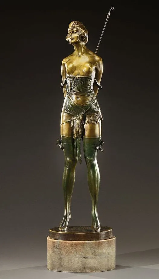 A full-length bronze statue of a woman with a golden torso and greenish legs, wearing a draped cloth around her waist and…