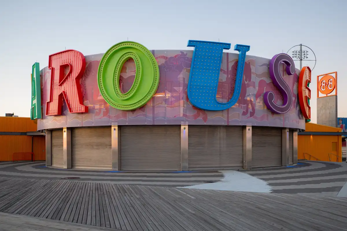 A large, colorful, retro-style sign spelling 'ROUSE' in bold, multi-colored letters (red, green, blue, purple) sits atop a…