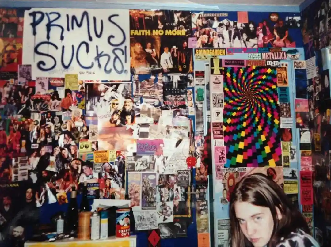 A wall covered in colorful music posters from bands like Faith No More, Soundgarden, and Metallica, with a large handwritten…