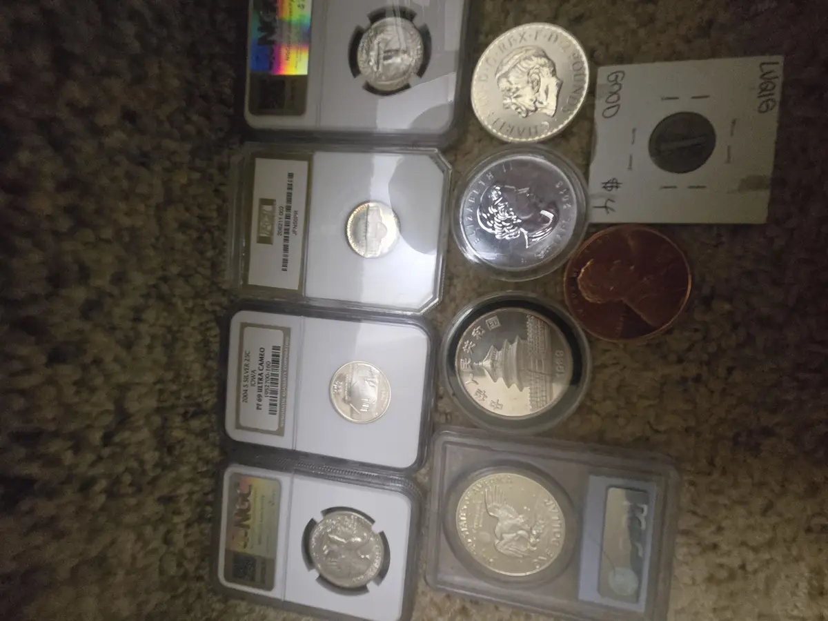 A collection of various coins, including several in protective NGC grading slabs, a British 2-pound coin, a Chinese 1989…