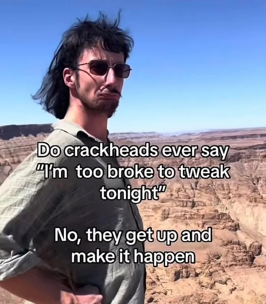 A man with dark hair, sunglasses, and a beard stands in a desert canyon with a serious, slightly smug expression. The text…