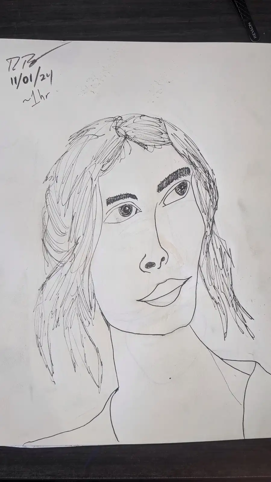 A hand-drawn black-and-white sketch of a person's face and shoulders on white paper, with messy hair and detailed eyes. In…