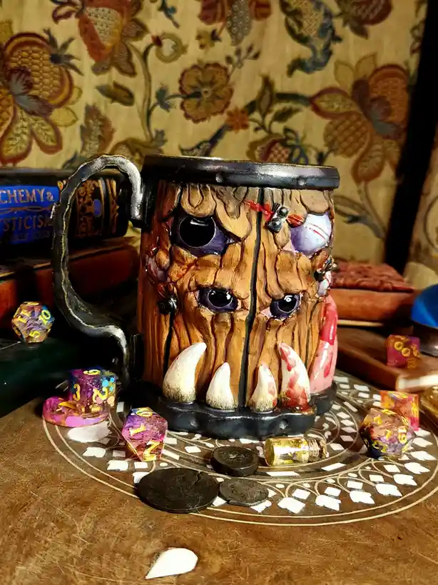 A heavily detailed, monstrous mug with a tree-like face, purple eyes, and blood-stained fangs sits on a patterned table…