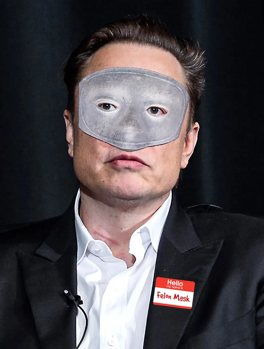 A man in a black suit and white shirt has a gray, textured mask covering his eyes and nose, leaving only his mouth and ears…