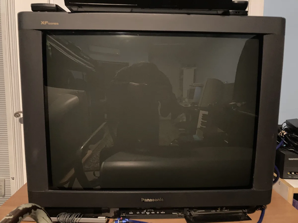 A black Panasonic TV with 'XF series' branding on top and 'Panasonic' on the bottom bezel, sitting on a wooden desk. The…