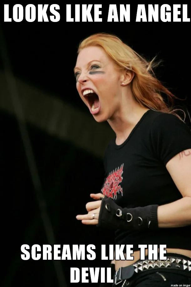 A woman with long red hair, wearing a black t-shirt, fingerless gloves, and a studded belt, is captured mid-scream with her…