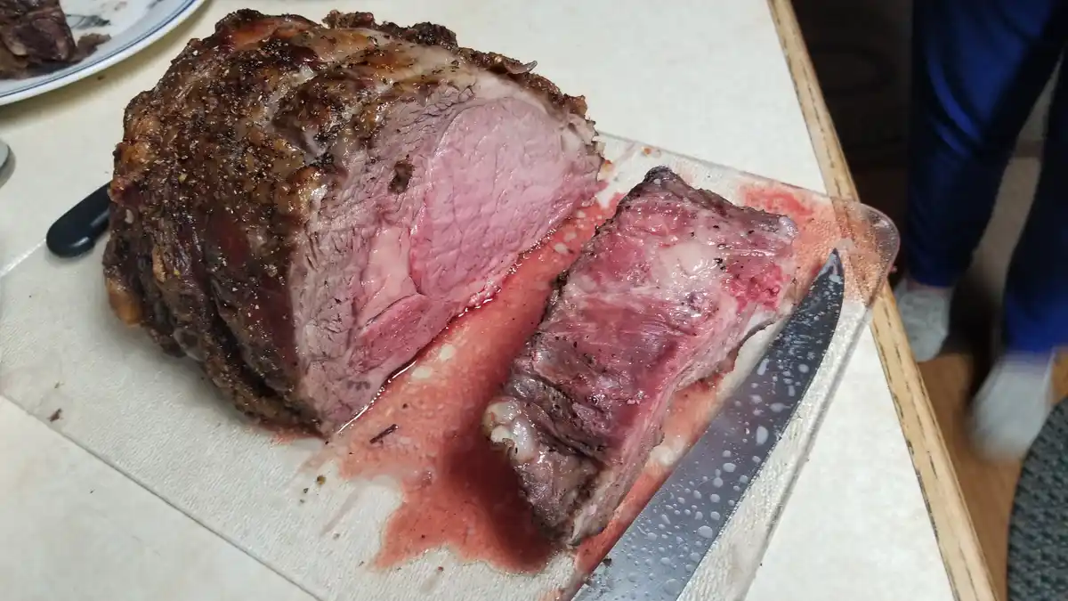 A large, sliced roast beef with a very pink, rare interior sits on a cutting board with a knife nearby, and the overlaid…