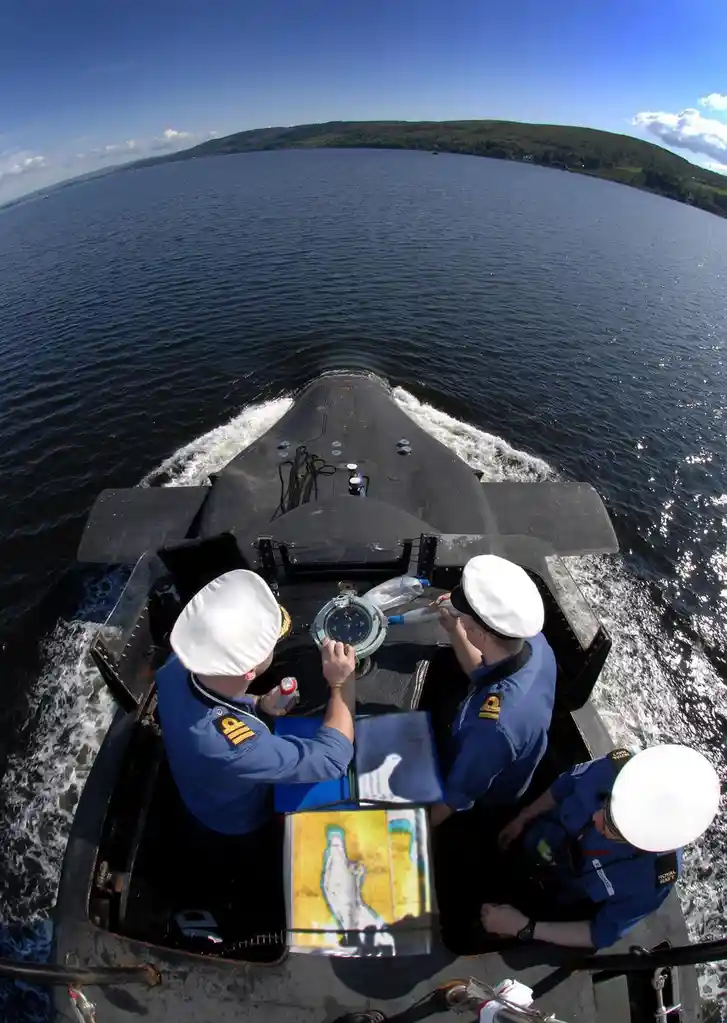 A Glimpse of Tradition: An Officer on Watch Aboard HMS Vanguard with Classic Compass and Map