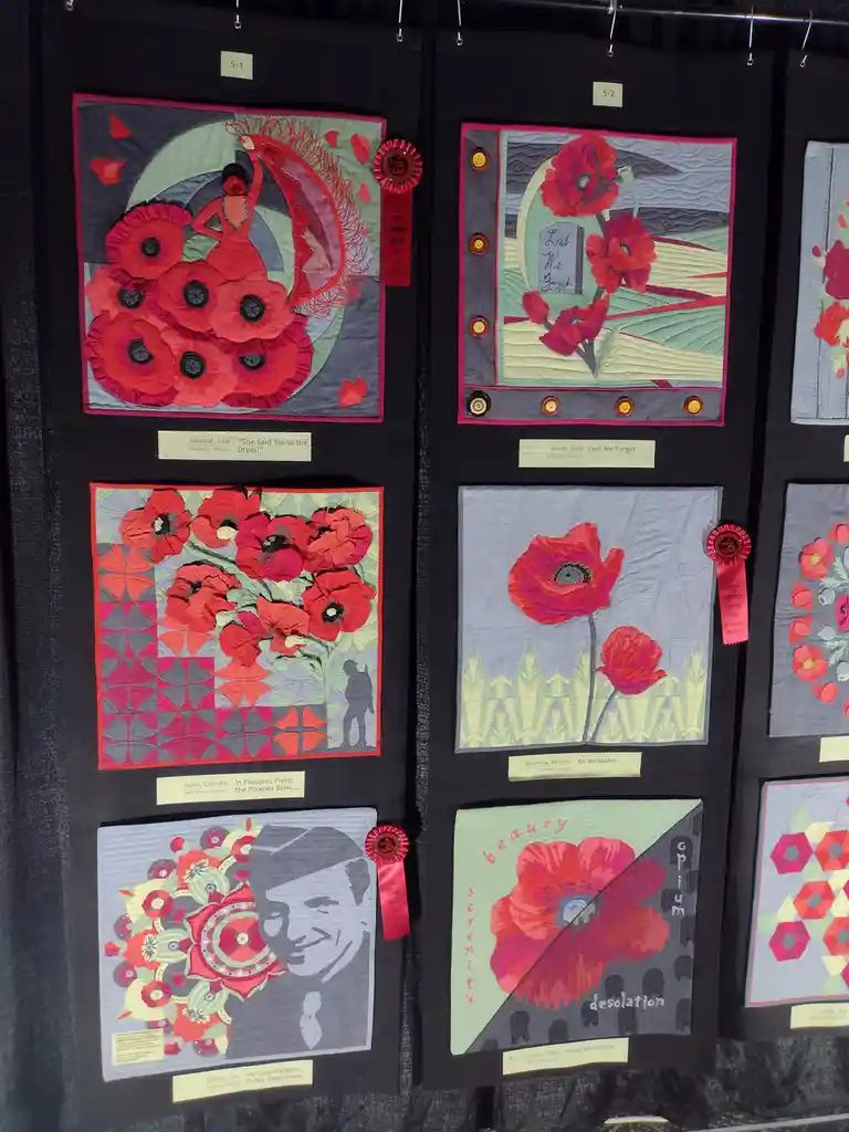 A display of six quilt art pieces featuring red poppies, each with unique designs and titles like 'She Said Yes to the…