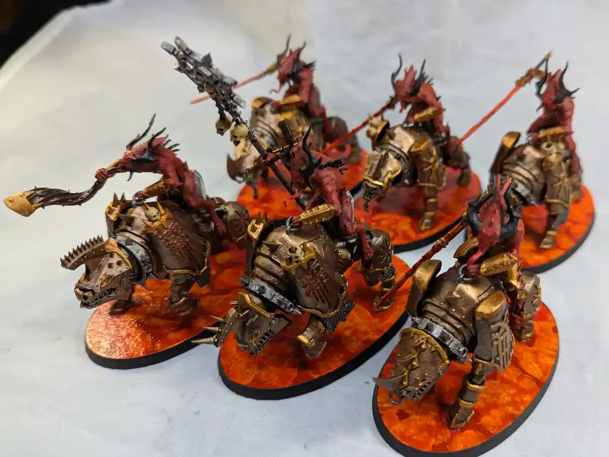 A photo of six intricately painted Warhammer 40,000 Chaos Daemons mounted on heavily armored, spiked beasts, each standing…