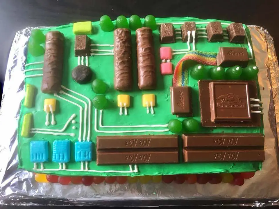 a rectangular cake covered in green frosting and decorated to resemble a computer circuit board, with white icing lines…