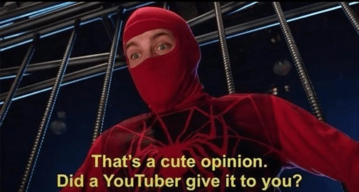 A person in a red Spider-Man costume with a red mask covering their face, standing behind metal bars in a dark setting. The…