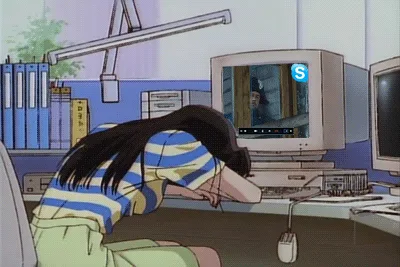A woman in a striped shirt is slumped over a desk, her head resting on her arms, in front of an old computer monitor. The…