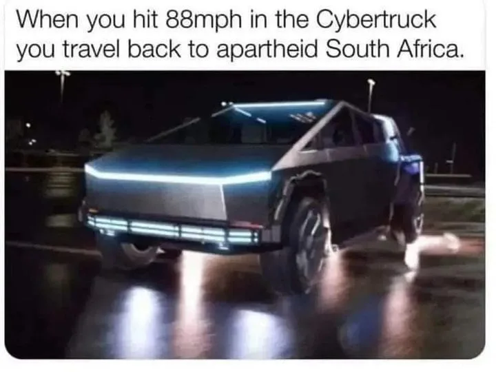 A dark, wet night scene featuring a silver Tesla Cybertruck driving on a road, its distinctive angular headlights glowing…