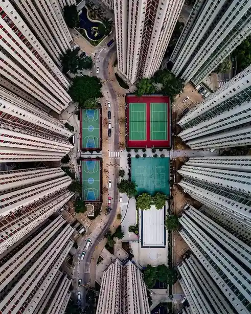An aerial view looking straight down into a dense urban area surrounded by tall apartment buildings. In the center, there…