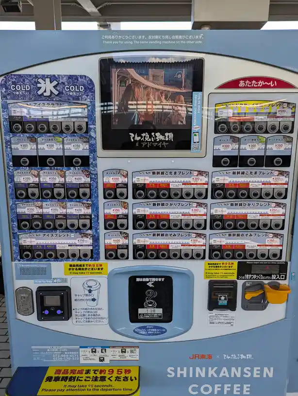 A Japanese coffee vending machine branded 'Shinkansen Coffee' with cold and hot beverage options, featuring a screen…