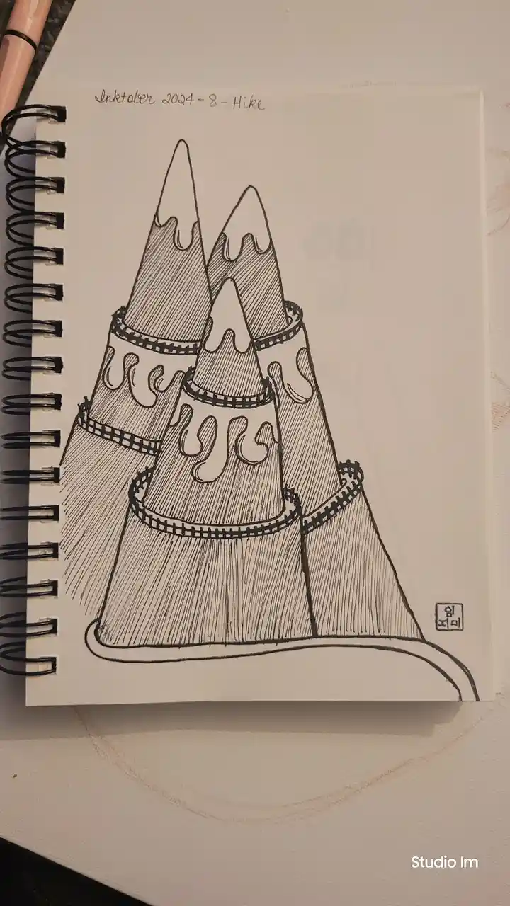 A black-and-white ink drawing in a spiral-bound sketchbook depicts three stacked, cone-shaped mountains with jagged peaks…