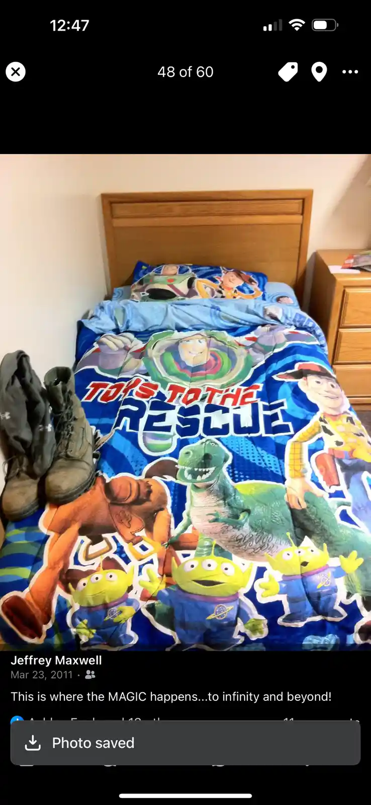 A child's bed with a blue 'Toys to the Rescue' comforter featuring Buzz Lightyear, Woody, Rex, and the Aliens. A pair of…