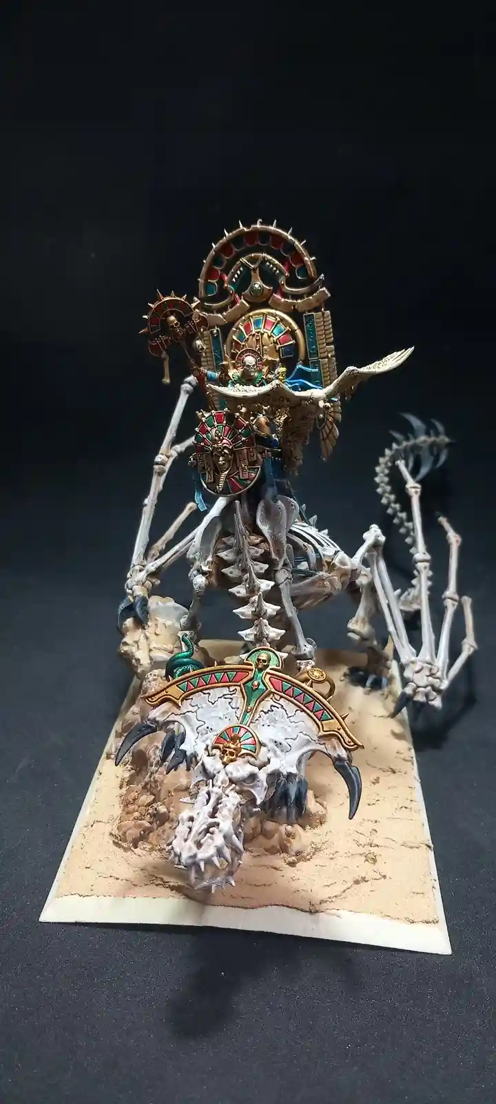 A highly detailed, painted miniature of a skeletal, multi-limbed creature with ornate golden and colored gemstone armor…