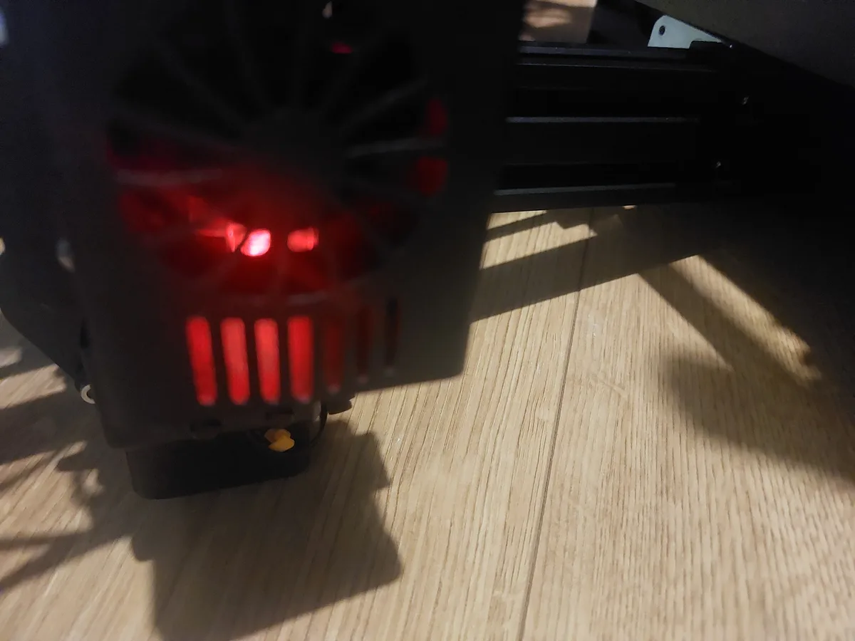 A close-up photo shows the back of a black computer case on a wooden floor, with red LED lights arranged to resemble angry…