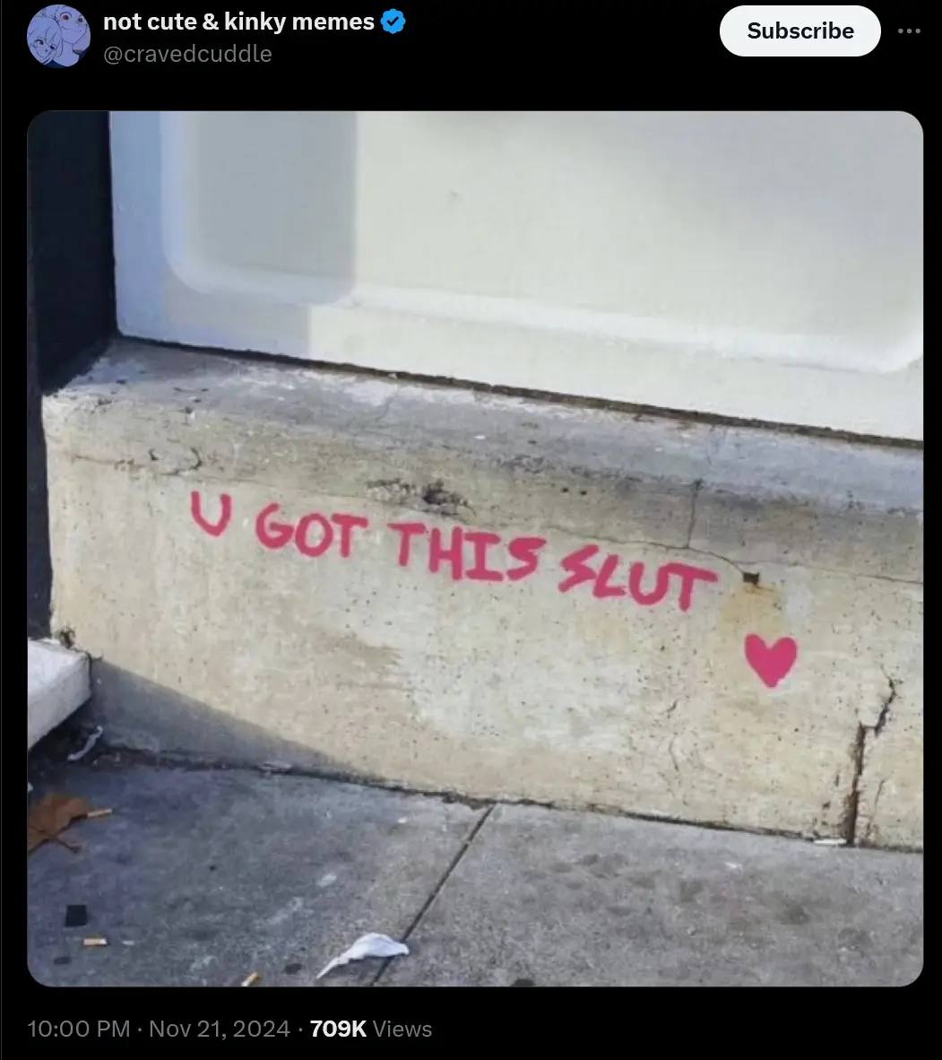 A close-up photo shows red spray-painted text on a concrete ledge outside a building, reading 'U GOT THIS SLUT' followed by…