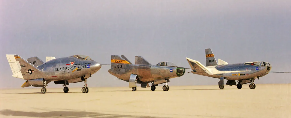 Three experimental aircraft, labeled U.S. Air Force X-24A, NASA 803, and NASA 804, are parked in a row on a desert runway…