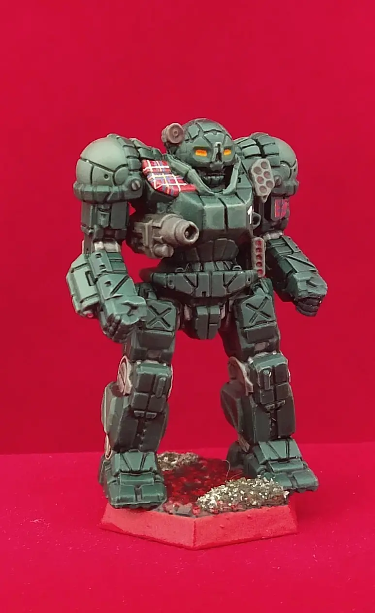 A green-painted, heavily armored humanoid robot miniature stands on a red hexagonal base against a solid red background. The…